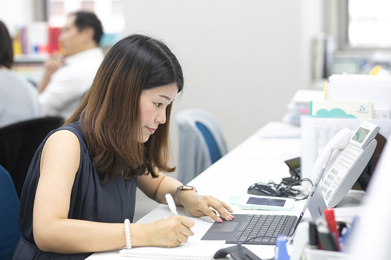 デスクワークをする秦さん